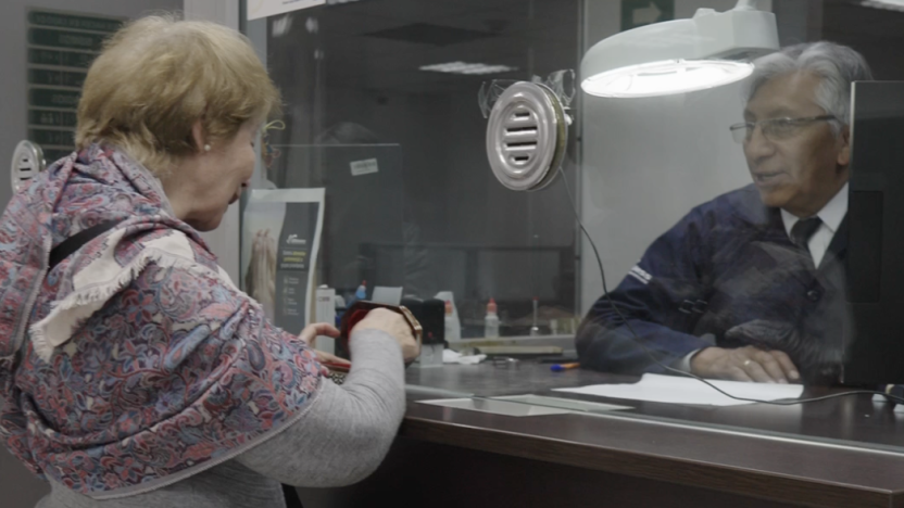 Funcionario del Biess revisando con una lupa de joyería cadenas y anillos de oro depositados como garantía prendaria.