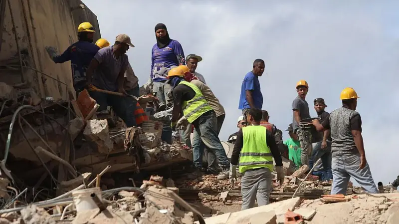 Voluntarios con cascos protectores cargando cajas de provisiones médicas hacia un avión de carga internacional.