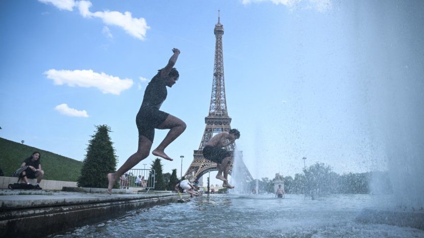 Ciudadanos franceses refrescándose en una fuente de agua pública en París durante un día soleado de verano.