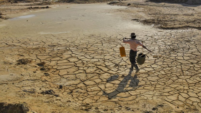 Termómetro marcando altas temperaturas sobre un terreno árido afectado por el calentamiento global.