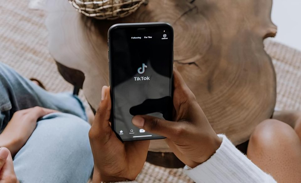 Persona usando smartphone con aplicación TikTok mostrando contenido sobre visas falsas en TikTok mientras consulta documentos migratorios