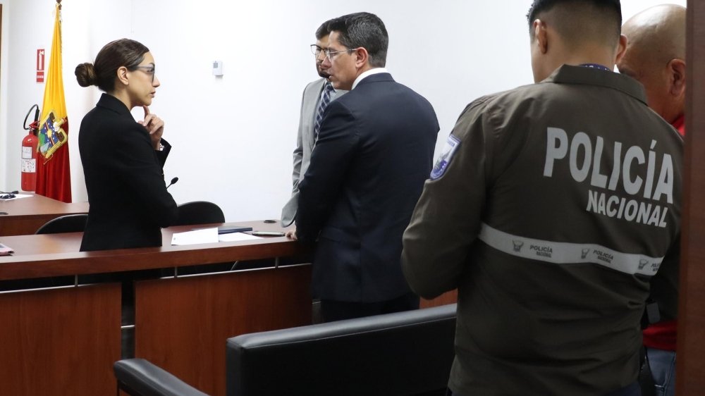 Sala de audiencias judicial ecuatoriana con silla vacía de jueza, mazo y expedientes sobre escritorio, simbolizando caso Villavicencio nuevo diferimiento