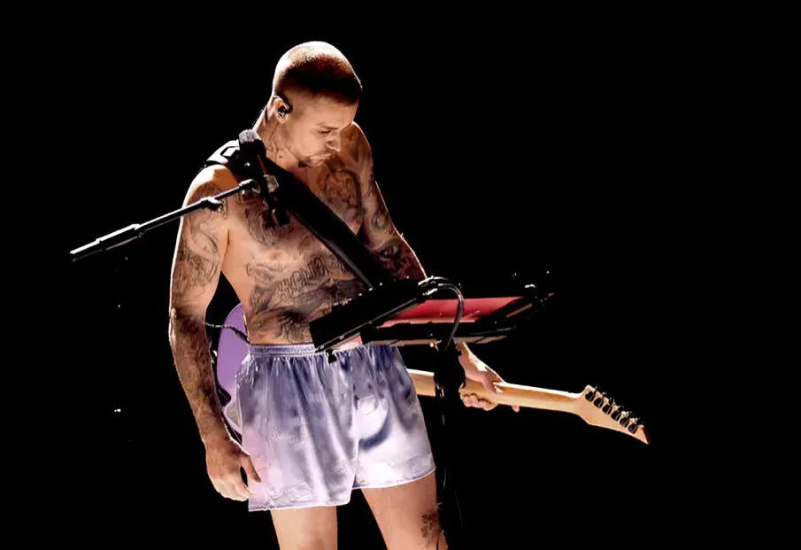 Justin Bieber en el escenario de los Grammy 2026 cantando solo en boxers grises y calcetines, con una guitarra eléctrica.