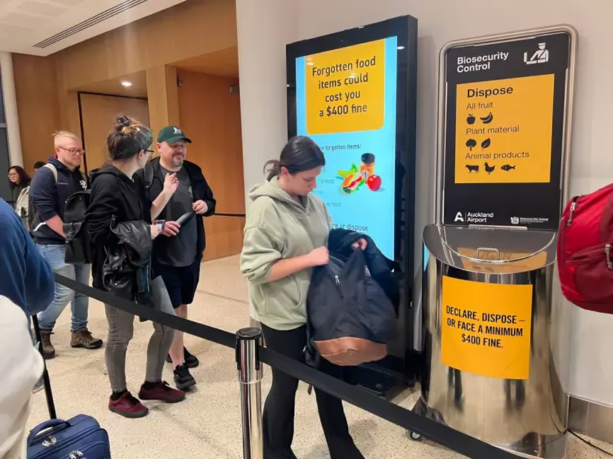 Multitud de personas con maletas en el aeropuerto de Auckland, Nueva Zelanda, abordando vuelos con destino a Australia.