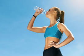 Persona bebiendo agua después de hacer ejercicio en un entorno al aire libre