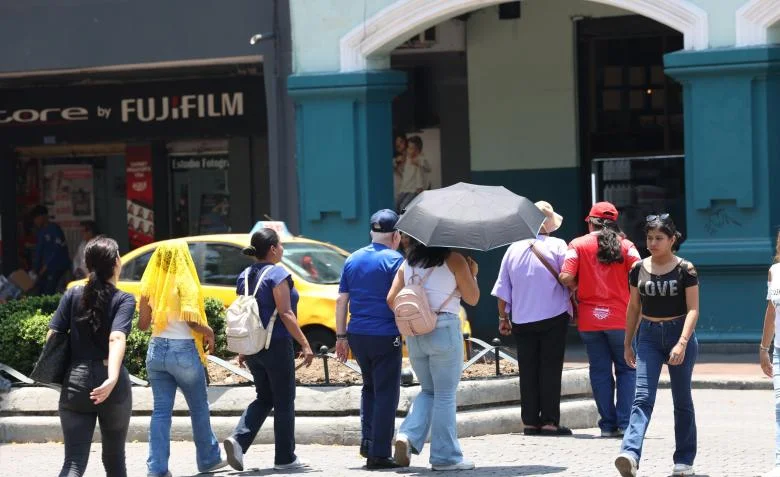 Persona aplicando protector solar en la playa de Guayaquil durante un día de intenso calor.