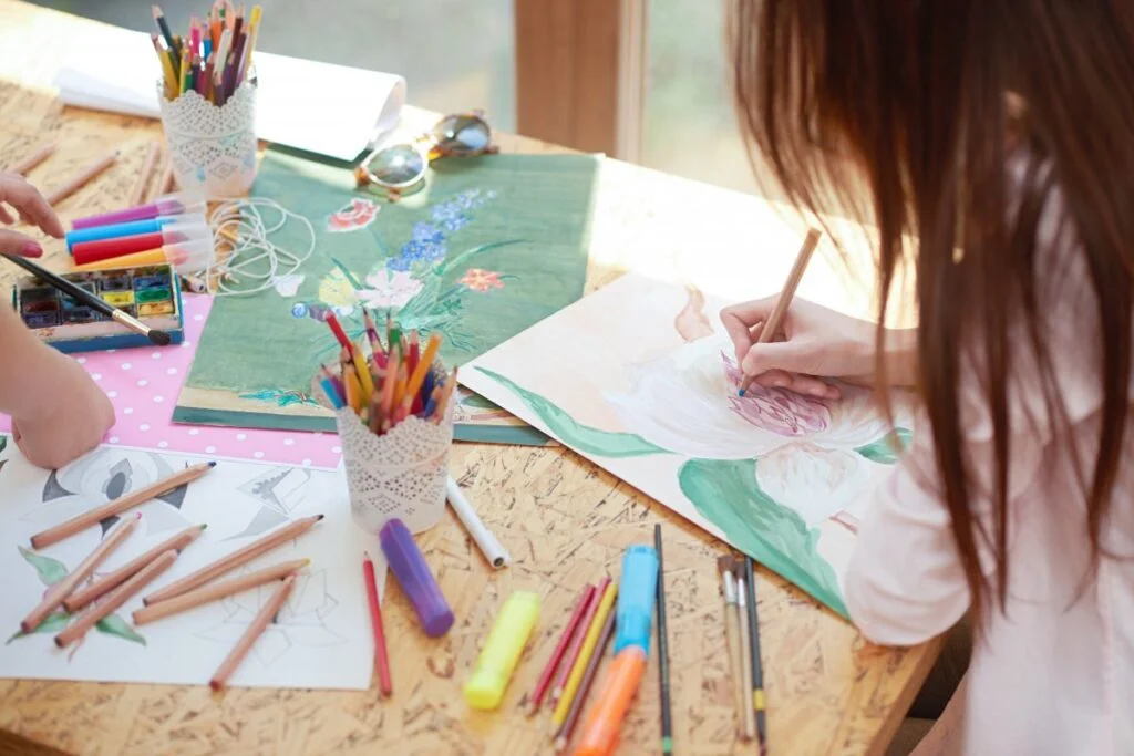 Niños sonriendo mientras pintan y participan en un taller de arte enfocado en el bienestar infantil.