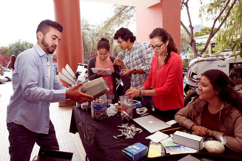 Personas clasificando dispositivos electrónicos para reciclaje en jornada educativa de la Universidad San Francisco de Quito