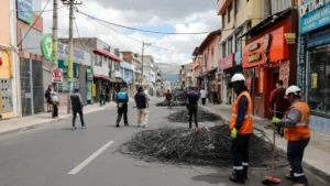 Operarios municipales enrollando cables en desuso retirados de postes en Cotocollao