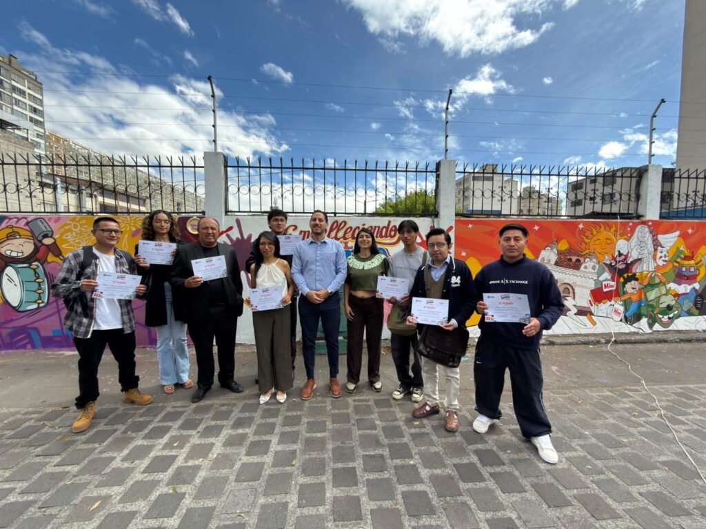 Artistas ecuatorianos pintando murales de arte urbano en quito en un espacio público de la ciudad.