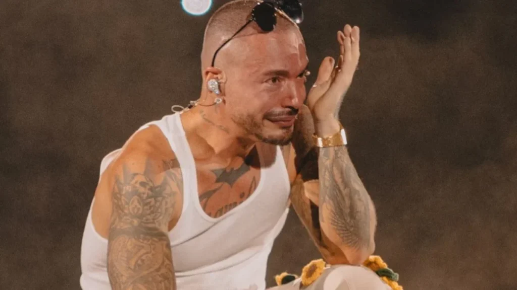 J Balvin posando sonriente en un evento público de música y moda internacional