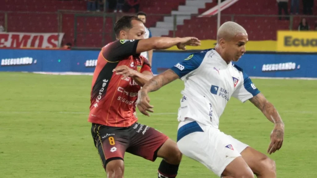 Deyverson disputa el balón ante la marca de la zaga de Deportivo Cuenca en Quito