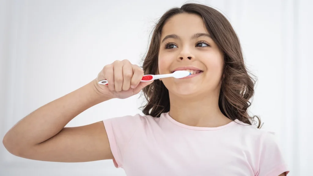 Niña sonriente cepillándose los dientes durante su rutina de salud bucal infantil