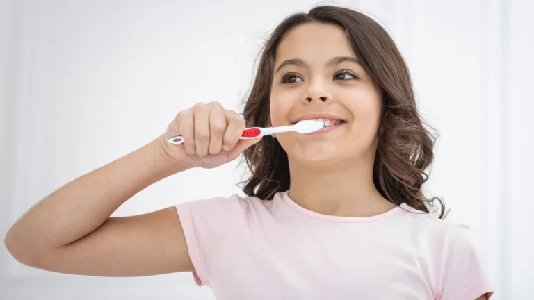 Niña sonriente cepillándose los dientes durante su rutina de salud bucal infantil