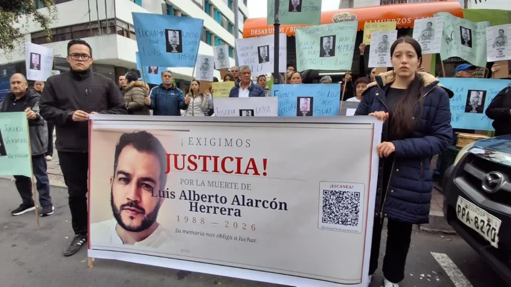 Familiares de Luis Alarcón sostienen carteles exigiendo justicia frente a la clínica dental