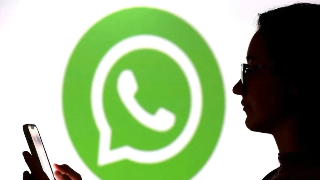 Mano sosteniendo un teléfono móvil inteligente con la aplicación de mensajería WhatsApp activa