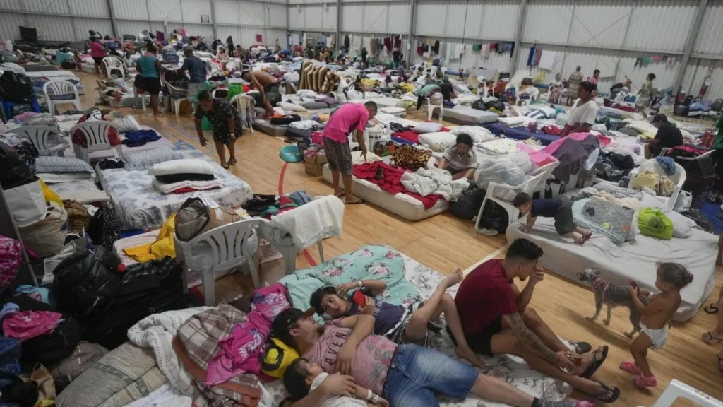 Madre y niñas ecuatorianas caminando en zona inundada tras desbordamiento por lluvias