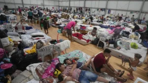Madre y niñas ecuatorianas caminando en zona inundada tras desbordamiento por lluvias