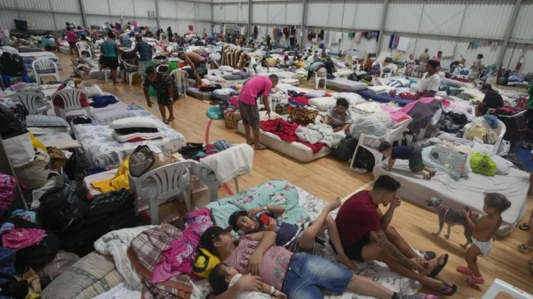 Madre y niñas ecuatorianas caminando en zona inundada tras desbordamiento por lluvias