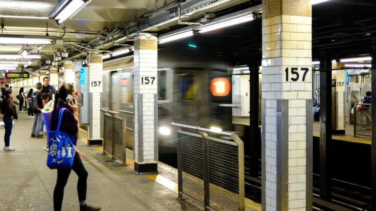 Andén subterráneo del metro de Nueva York con vías y trenes de pasajeros