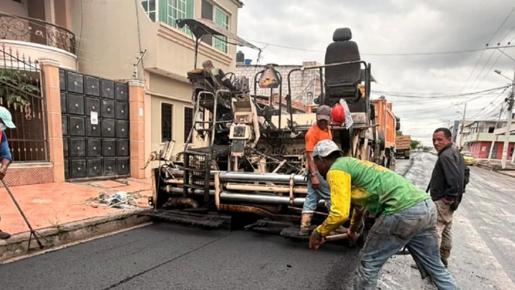 Maquinaria pesada y volquetes cargando material pétreo para asfalto vial